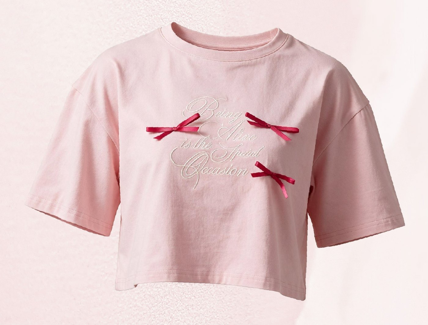 The SHOPLOOOH Being Alive Is the Special Occasion Tee in soft pink with embroidered script and three satin bows