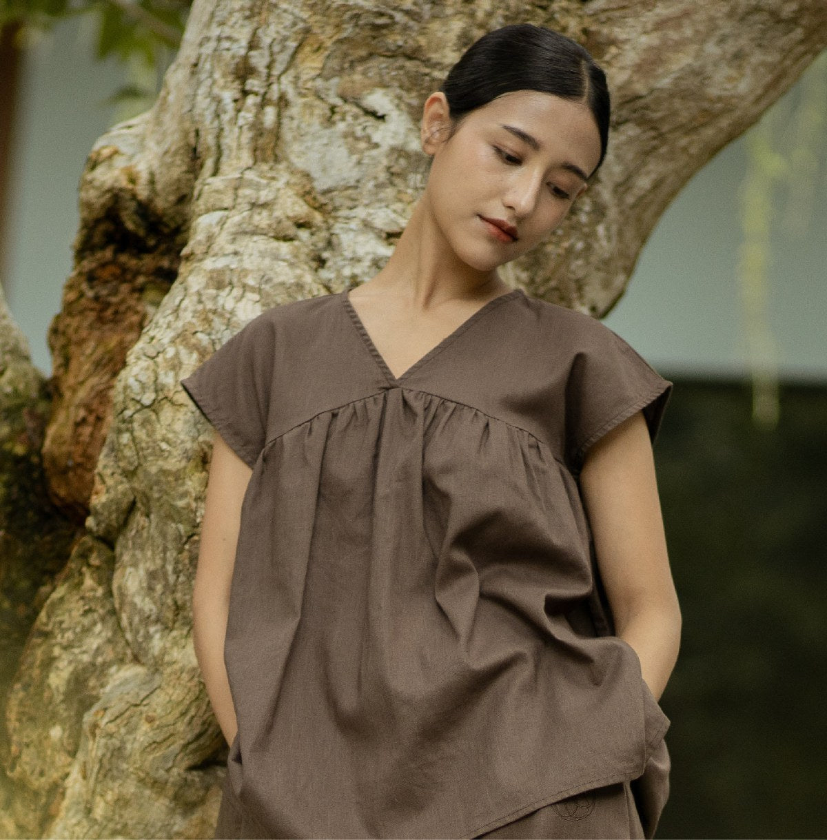 Re Collection — Reset & Reconnect. Leaning against an old tree in the SHOPLOOOH warm brown cotton-linen set