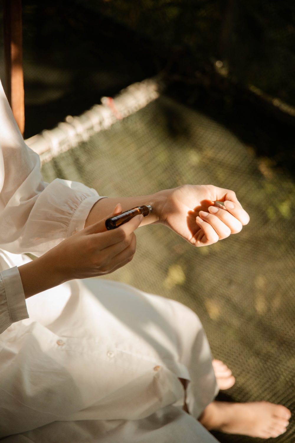 Applying the SHOPLOOOH Silent Wood essential oil roll-on to the wrist in soft morning light